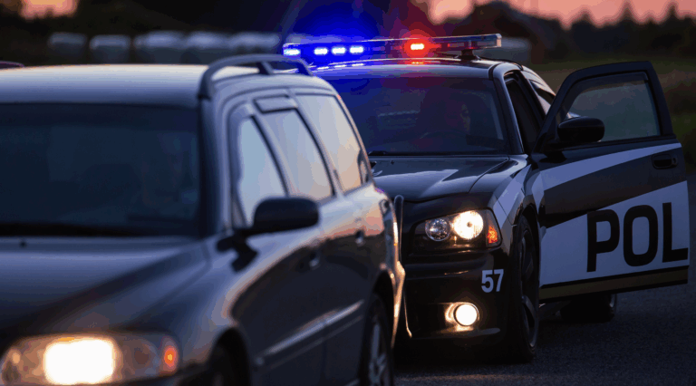 Photo of a traffic stop with a police cruiser pulling over a black van on the side of the road | Daniel Stark Law